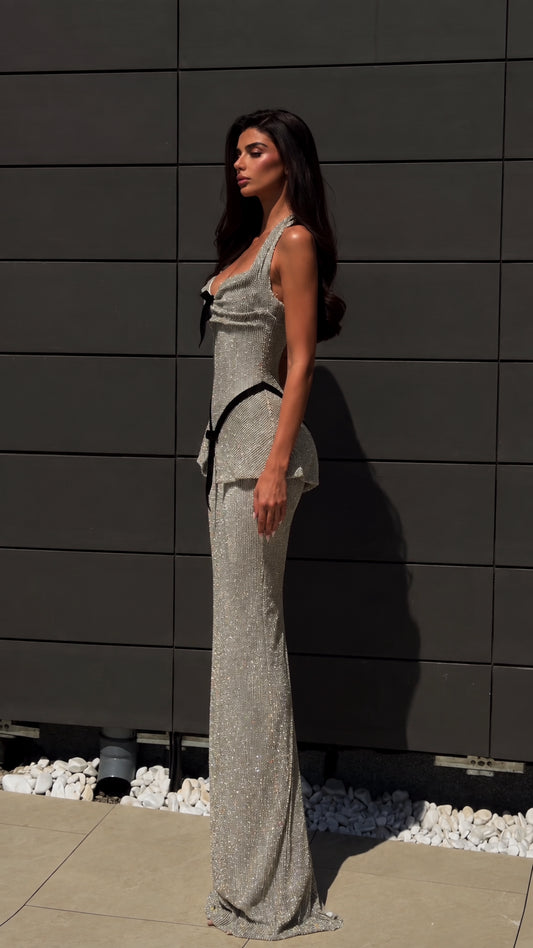 Side angle of model in silver sparkling halter gown showing peplum waist